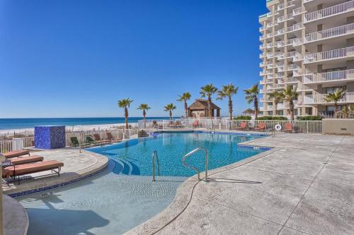 a swimming pool next to a building and the beach at Escapes to the Shores in Orange Beach