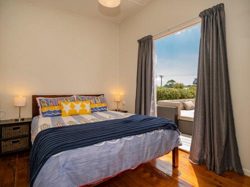 Un dormitorio con una cama y una ventana grande. en Pipi Palace - Whangamata Bach, en Whangamata