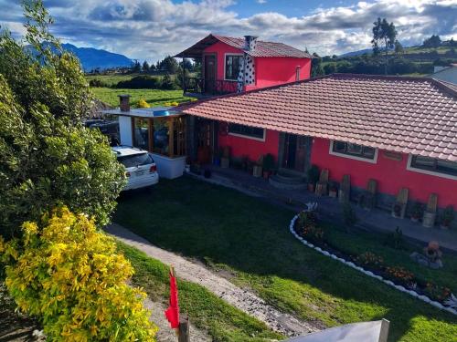 a red house with a red roof and a yard at Ruta de los volcanes in Machachi