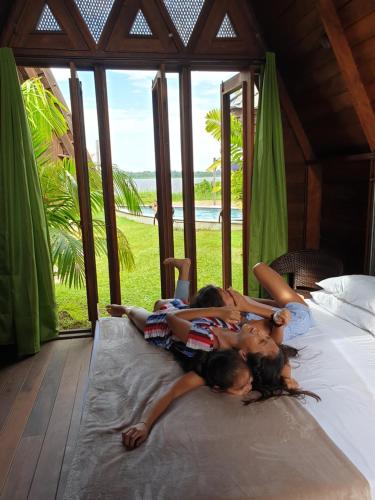 two girls laying on a bed in a bedroom at Houttuyn Wellness River Resort in Paramaribo