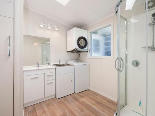 a white bathroom with a sink and a shower at Wharewaka Hideaway - Wharewaka Holiday Home in Taupo