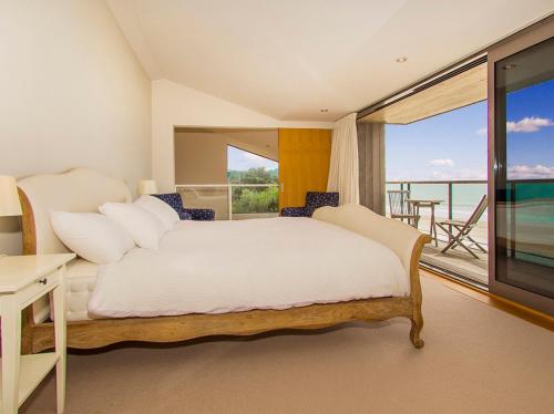 a bedroom with a bed and a view of the ocean at The Breakers - Whangapoua Executive Holiday Home in Whangapoua
