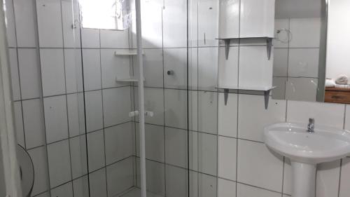a white tiled bathroom with a sink and a shower at Edifício Belio in Cascavel