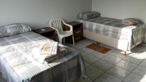 a bedroom with two beds and a desk and a chair at Edifício Belio in Cascavel