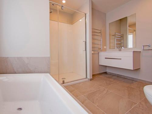 a bathroom with a tub and a sink and a shower at Tattletails Rest - Whitianga Holiday House in Whitianga