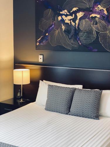 a bed with two pillows and a painting on the wall at ibis Styles Broken Hill in Broken Hill