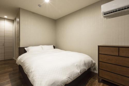 a bedroom with a large white bed and a dresser at Kyo no yado en in Kyoto