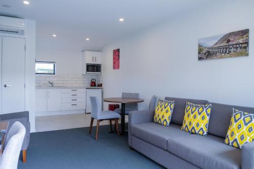 a living room with a couch and a table and a kitchen at ASURE Central Gold Motel Cromwell in Cromwell