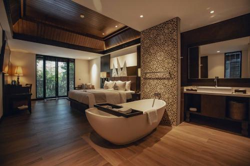 un bagno con letto e vasca in una camera di The Vira Bali Boutique Hotel & Suite a Kuta