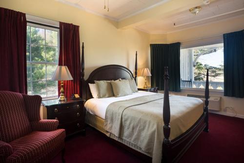 a bedroom with a bed and a chair and windows at Green Park Inn in Blowing Rock