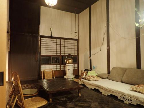 uma sala de estar com um sofá e uma mesa em Kominka Guesthouse Hagi Akatsukiya em Hagi