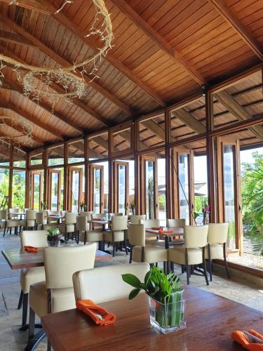 un restaurante con techos de madera, mesas y sillas en Houttuyn Wellness River Resort en Paramaribo