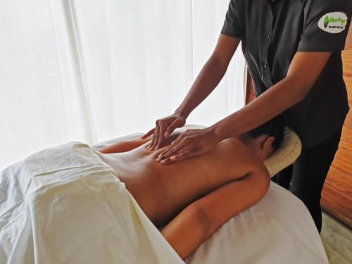 a man getting a back massage from a therapist at Houttuyn Wellness River Resort in Paramaribo