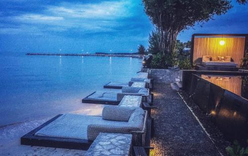 a row of benches next to the water at night at Cher Resort in Cha Am