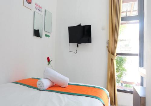 a room with a bed with a flat screen tv at Hotel Jogja Kili Suci By Simply Homy in Yogyakarta