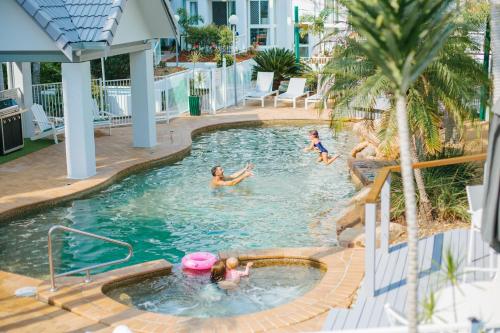 a group of children playing in a swimming pool at The Bay Apartments Coolangatta in Gold Coast
