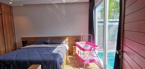 een slaapkamer met een bed en een roze stoel bij Villa Kamala close to the beach in Kamala Beach
