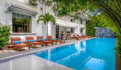 an outdoor swimming pool with chairs and a house at White Mansion 白色公馆 in Phnom Penh