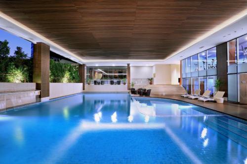 a large swimming pool in a building with a house at Atria Hotel Gading Serpong in Serpong
