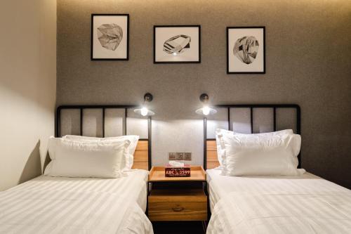 two beds in a room with three pictures on the wall at SVOK Hotel in Tawau