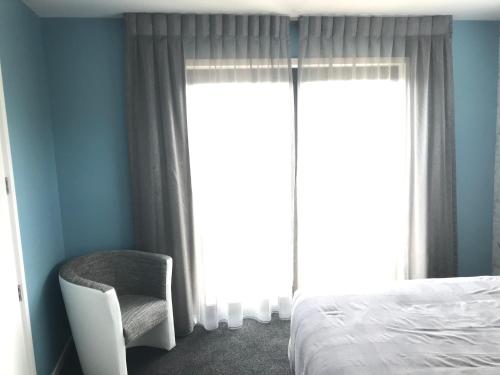 a bedroom with a bed and a chair next to a window at Gerding Haven in Napier
