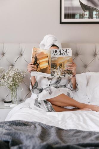 a woman sitting on a bed reading a magazine at The Lurline Randwick in Sydney