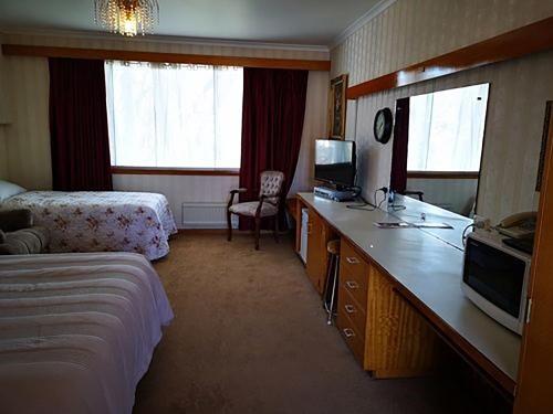 a hotel room with a bed and a desk with a television at Motel Mayfair on Cavell in Hobart