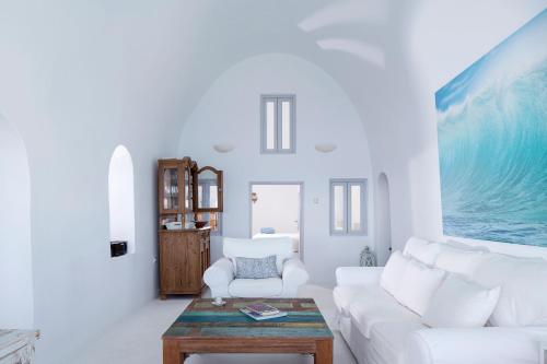 Sala de estar blanca con sofá blanco y mesa en Gaia Villa, en Imerovigli