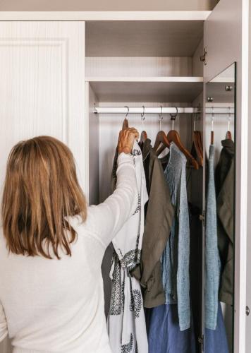 a woman is standing in a closet holding a tie at The Lurline Randwick in Sydney