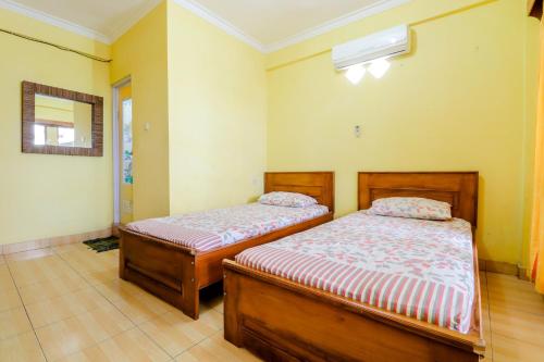 two beds in a room with yellow walls at Adinda Beach Hotel and Villa in Bantul