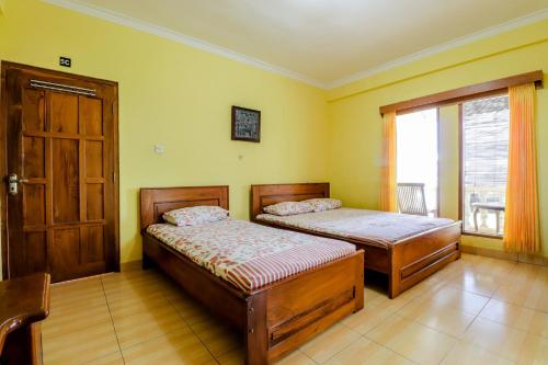 two beds in a room with a door and a window at Adinda Beach Hotel and Villa in Bantul