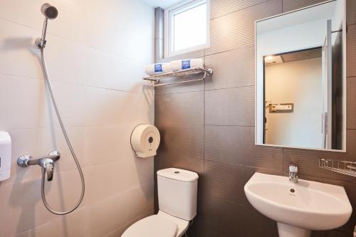 a bathroom with a toilet and a sink and a mirror at ibis budget Singapore Bugis in Singapore