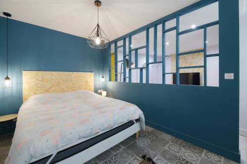a bedroom with a bed and a blue wall at Gîte de la Frête in Carvin
