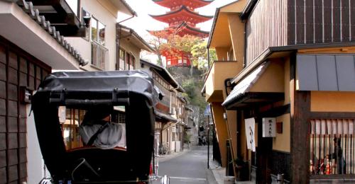 a street with buildings and a person in a car at Miyajima Shiro in Miyajima