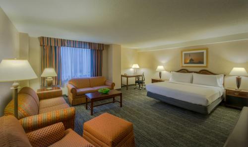 a hotel room with a bed and a couch and chairs at Holiday Inn Arlington at Ballston by IHG in Arlington