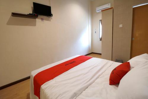 a bedroom with a white bed with red pillows at RedDoorz Plus near Universitas Sumatera Utara in Medan