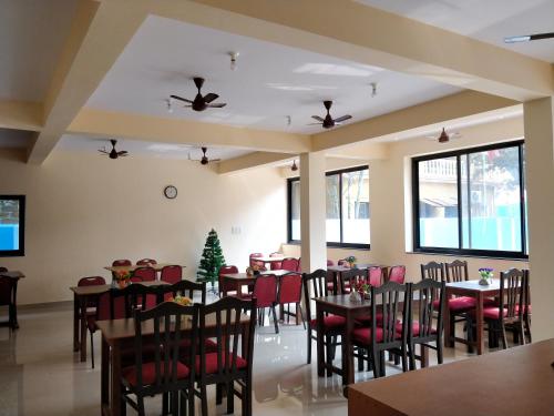 uma sala de jantar com mesas e cadeiras e uma árvore de Natal em Dom's Inn em Calangute