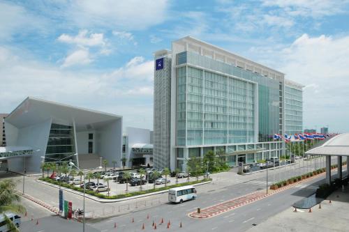 a large glass building with a bus in front of it at Novotel Bangkok IMPACT in Nonthaburi