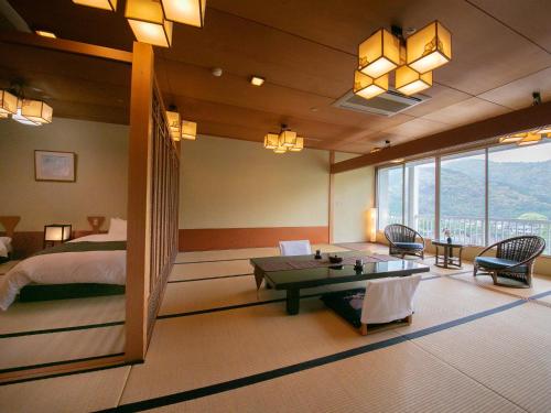 1 dormitorio con cama, mesa, cama y ventana en Iwakuni Kokusai Kanko Hotel, en Iwakuni