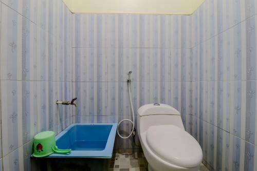 a bathroom with a toilet and a blue tub at Penginapan Barokah in Kemadang