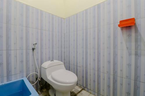 a bathroom with a white toilet and a blue tub at Penginapan Barokah in Kemadang