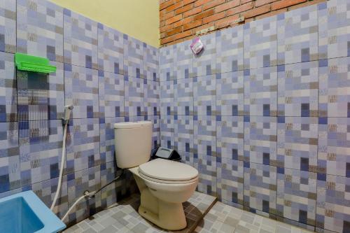 a bathroom with a toilet in a room with tiles at Penginapan Barokah in Kemadang