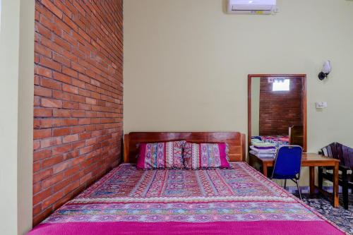 a bed in a room with a brick wall at Penginapan Barokah in Kemadang