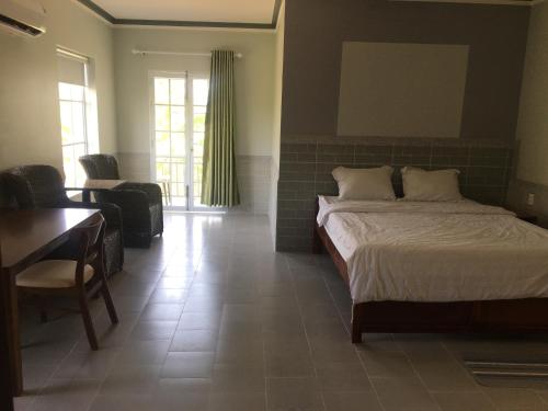 a bedroom with a bed and a desk and a chair at Aurora Mekong Hotel in Cai Be