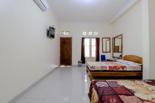 a white room with two beds and a mirror at Penginapan Barokah in Kemadang