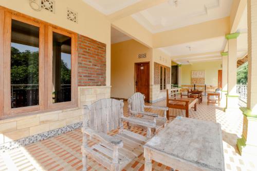 a porch with chairs and a table and windows at Penginapan Barokah in Kemadang