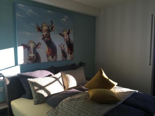 a bedroom with a bed with paintings of cows on the wall at Astrid's Pension in Winterberg