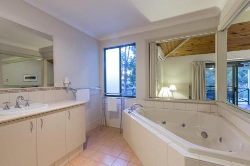 ein Badezimmer mit einer Badewanne, 2 Waschbecken und einem großen Spiegel in der Unterkunft Bushy Lake Chalets in Margaret River Town