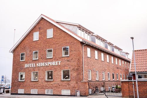 a large brick building with a sign that reads hotel servicesport at Hotel Sidesporet in Holbæk