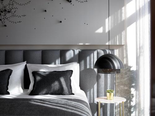 Heritage Hill Hotel في أثينا: سرير مع وسائد سوداء وبيضاء ومصباح